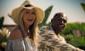 Holden and Brunson in the sunshine, she in off-the-shoulder blouse and straw hat