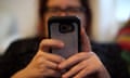 a blurred-out woman's face in the background taps into her mobile phone