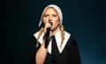 Self Esteem with a white bonnet holding a microphone.