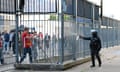 Anti-riot policeman sprays teargas at Liverpool fans on the other side of a gate