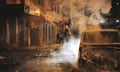 Firefighters aim a hose at a smouldering building