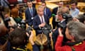 Nigel Farage speaks while surrounded by journalists and photographers